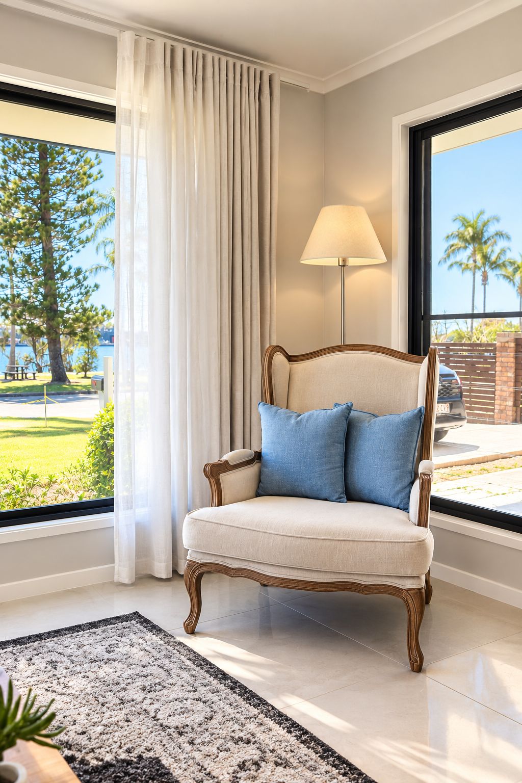 A chair with a lamp and a view of a lake and palm trees.