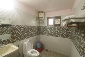 A bathroom with a tiled mosaic backsplash, a white toilet, a sink, a red trash bin, and a towel rack. - Birders Den Eco Resort (Nainital)