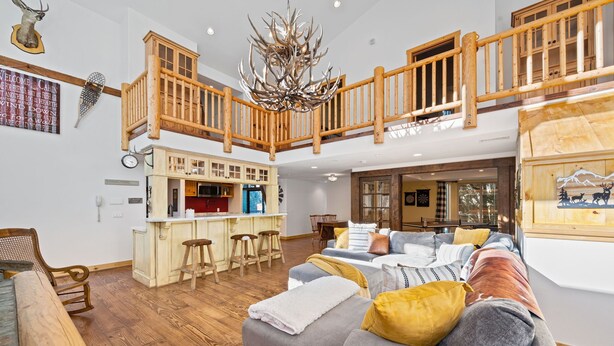 A spacious living area with a high ceiling, wooden staircase, and a cozy seating arrangement. - Spacious, Luxury, Picturesque "Mountain High Manor"- Ski Resort Town! (Wrightwood)