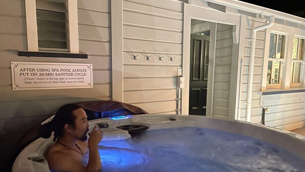Eine Person in einer Whirlwanne, mit einem Schild, das einen 20-minütigen Reinigungszyklus nach Benutzung des Spa-Pools anzeigt.