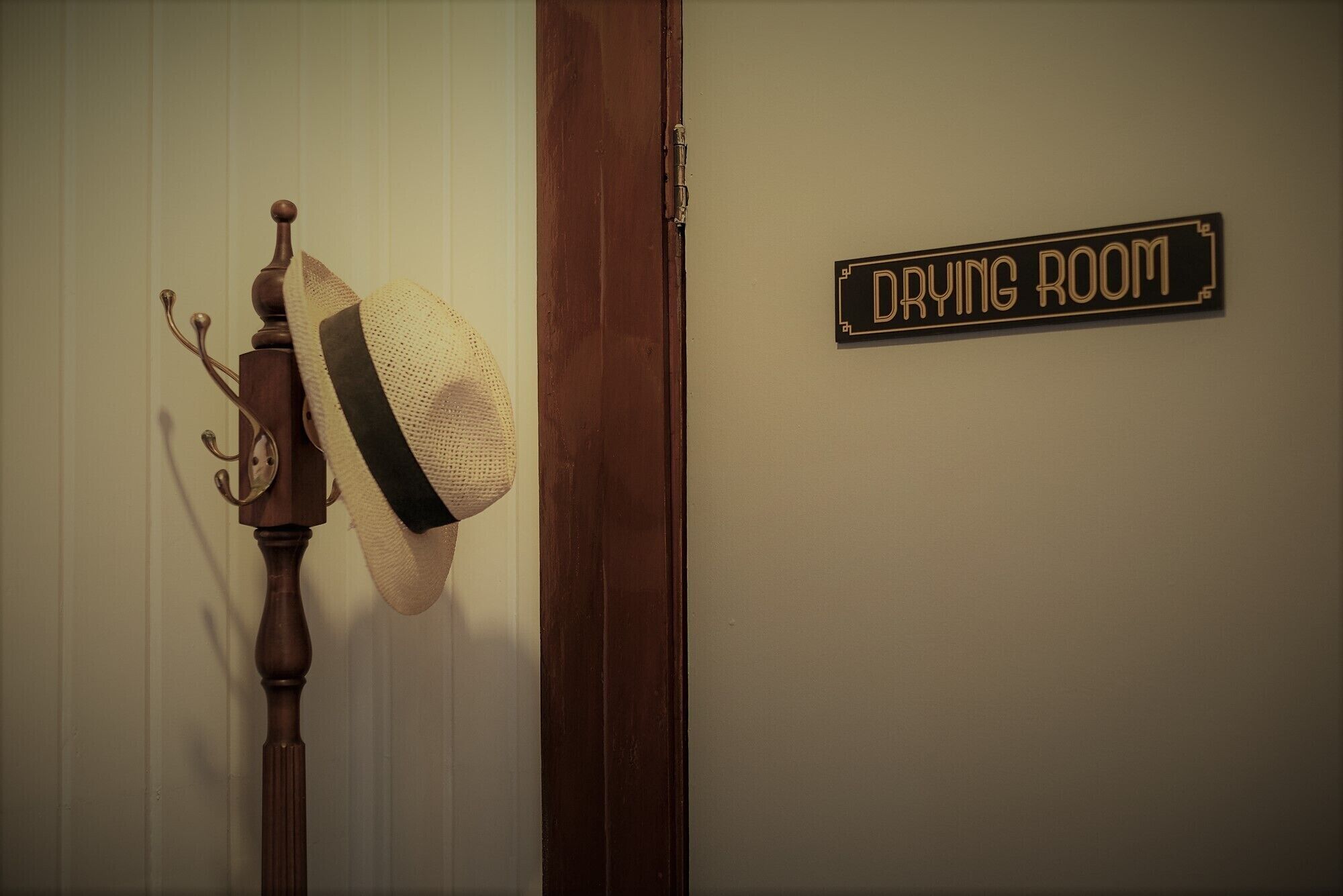 Una porta amb un rètol que diu "DAYING ROOM" i un barret penjat en un penjall.