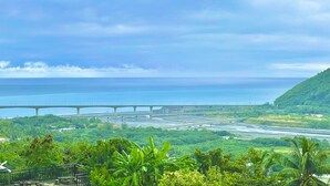 Eine Küstenlandschaft mit einer Brücke, üppigem Grün und Blick aufs Meer.