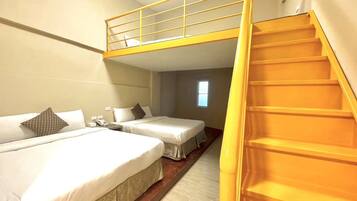 A hotel room with a bunk bed, a single bed, and a staircase.