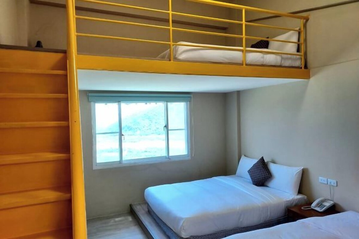Habitación con literas, una mesita de noche y un teléfono.