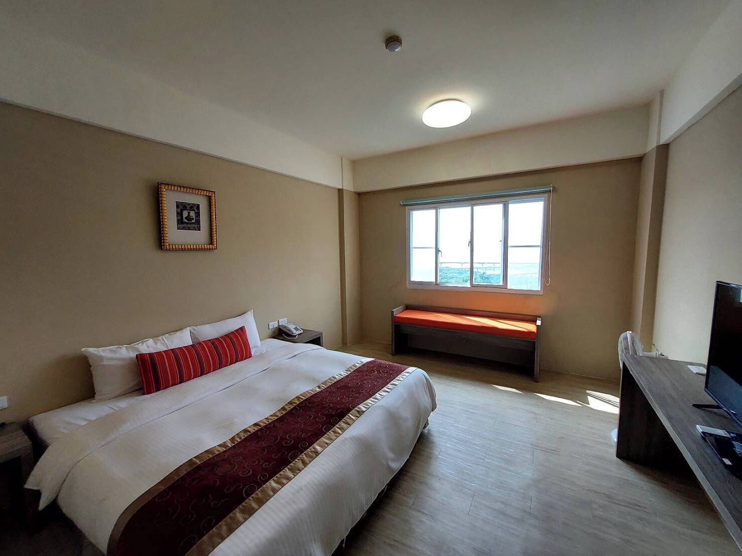 Une chambre d’hôtel avec un grand lit, un bureau avec un ordinateur, une fenêtre donnant sur un beau paysage et une table de chevet avec un téléphone.