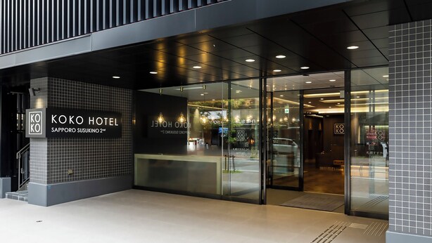 Der Eingang des Koko Hotels mit modernem Design, Glasüren und einem sichtbaren Empfangsbereich.