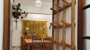 Un coin repas avec une table et des chaises en bois, une plante suspendue et un lustre.