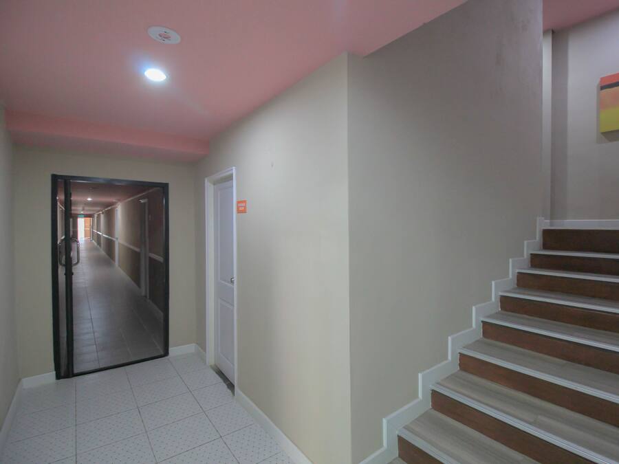 Un couloir avec un escalier, une porte et une œuvre d’art accrochée au mur.