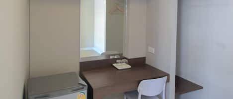 Una habitación pequeña con escritorio, silla y un refrigerador.
