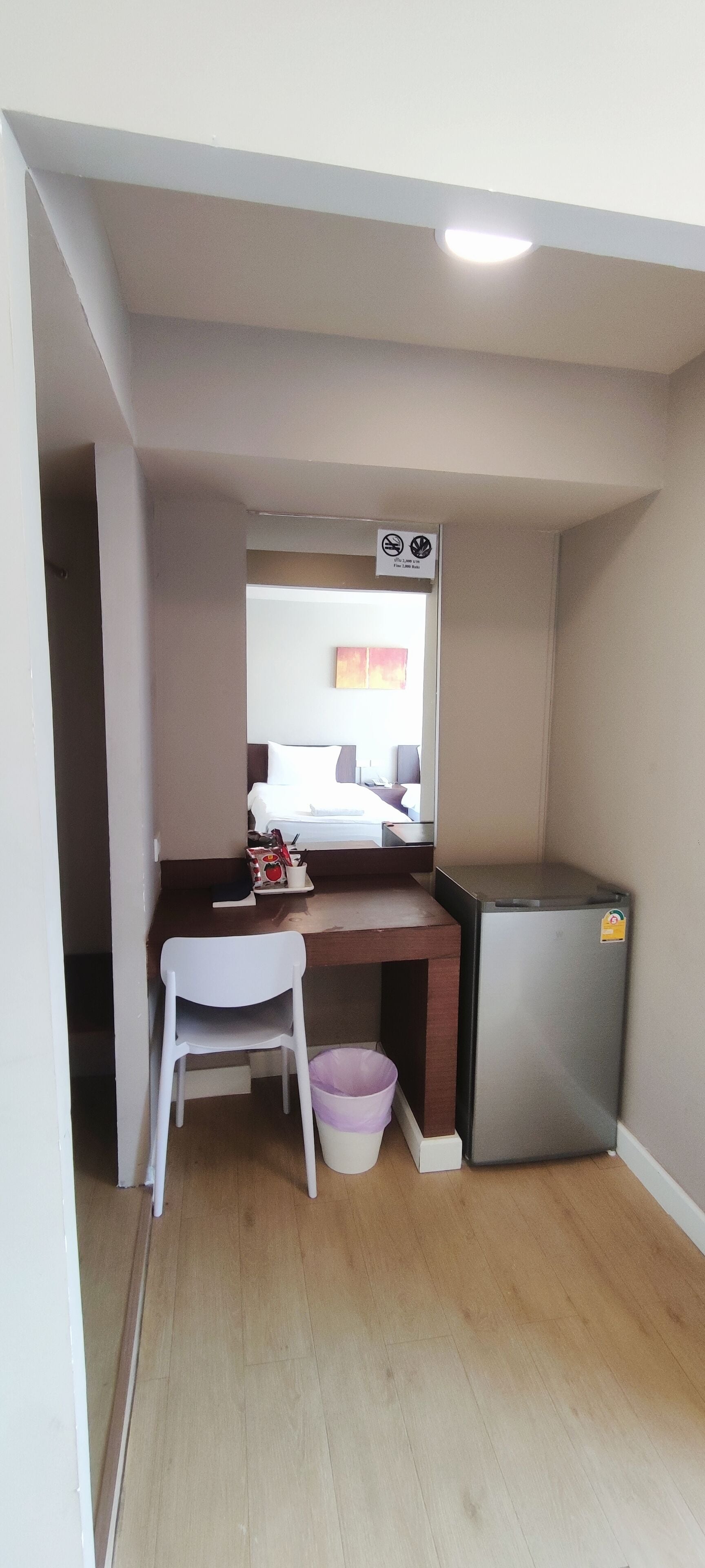 Ein kleines Zimmer mit Schreibtisch, Stuhl und kleinem Kühlschrank.