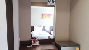 Ein kleines Zimmer mit Schreibtisch, Stuhl und kleinem Kühlschrank.