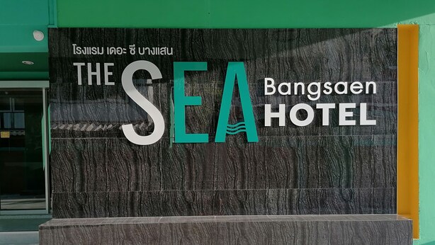 A sign for The SEA Hotel with a modern design and Thai text.