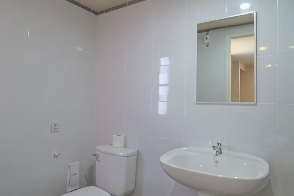 Un baño con inodoro, lavamanos y espejo.