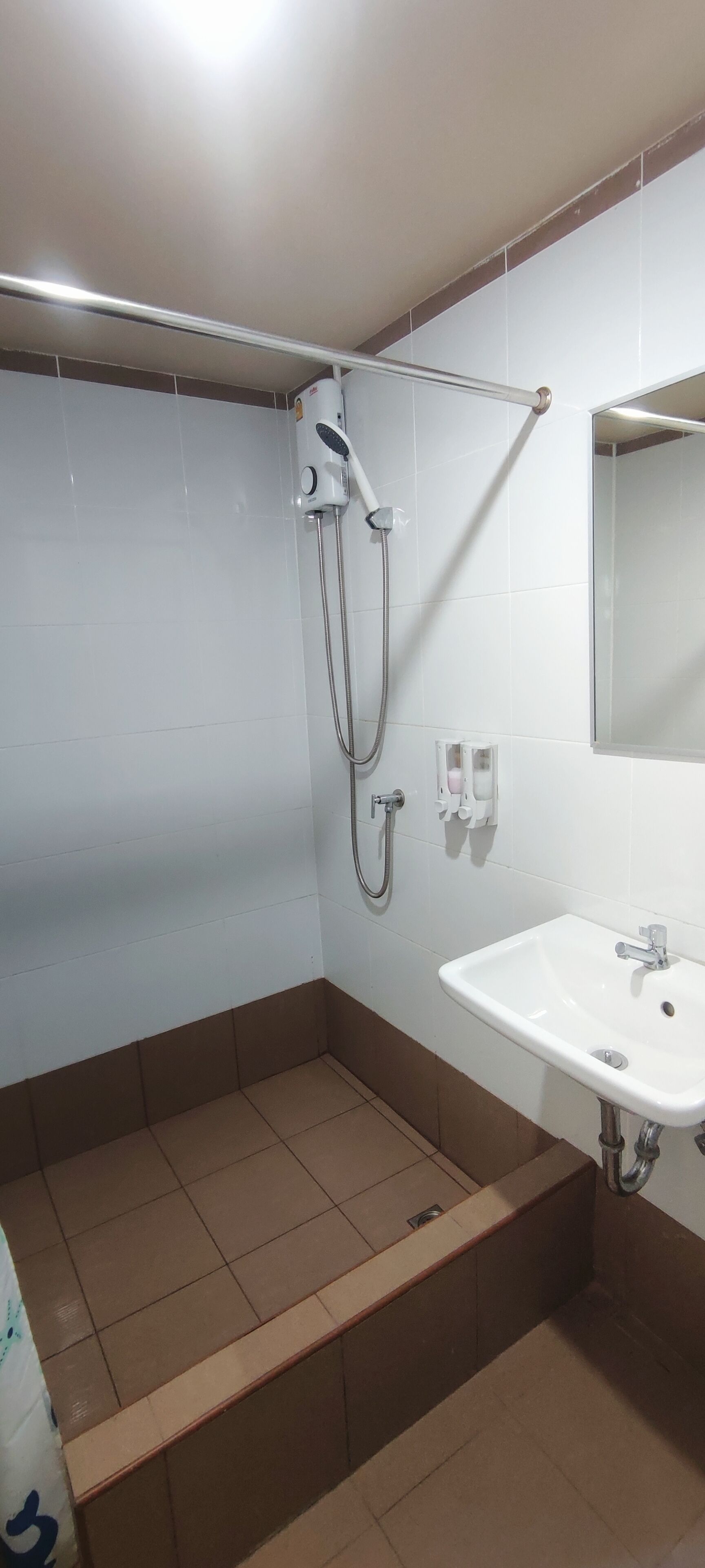 A bathroom with a shower, a sink, and a mirror.