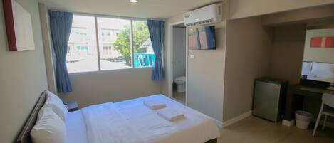 Habitación de hotel con cama, escritorio, aire acondicionado y vistas al exterior.