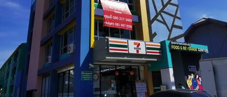 Un immeuble à plusieurs étages abritant un magasin 7-Eleven au rez-de-chaussée, un centre de restauration et une enseigne indiquant « The SEA ».