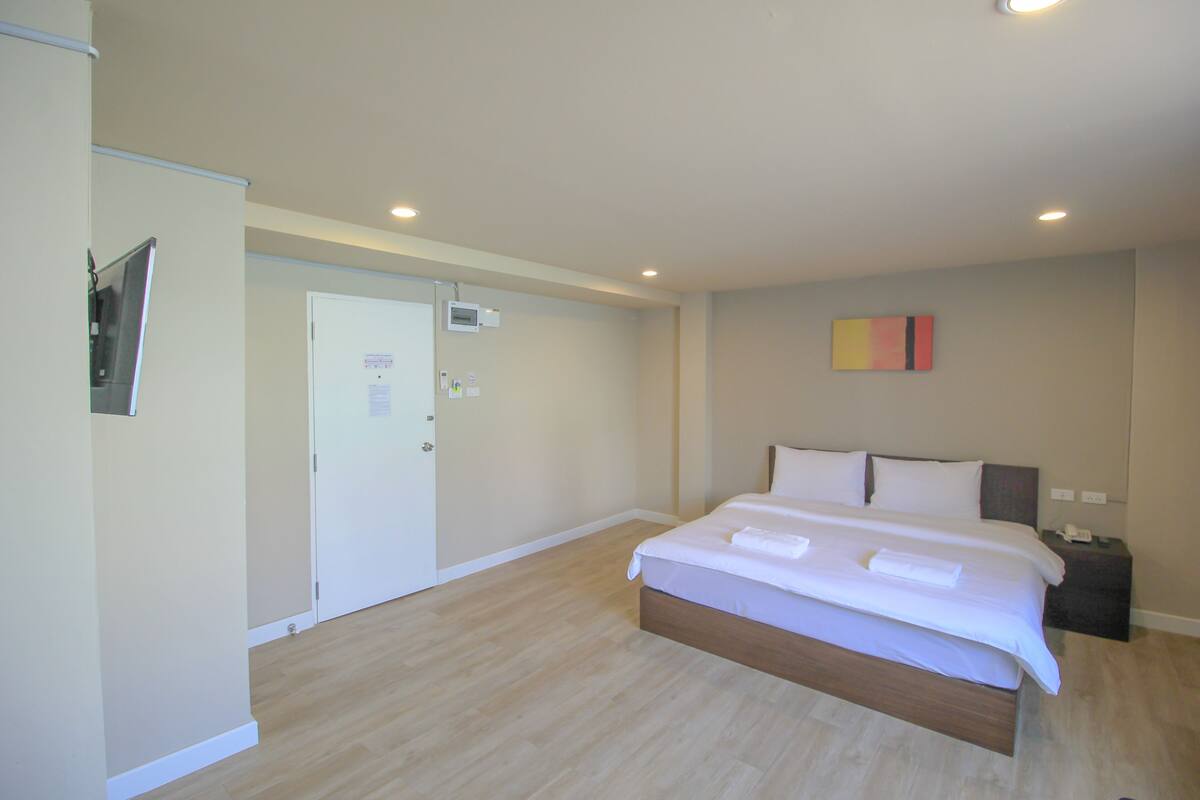 A bedroom with a large bed, a bedside table, a nightstand, and a door.