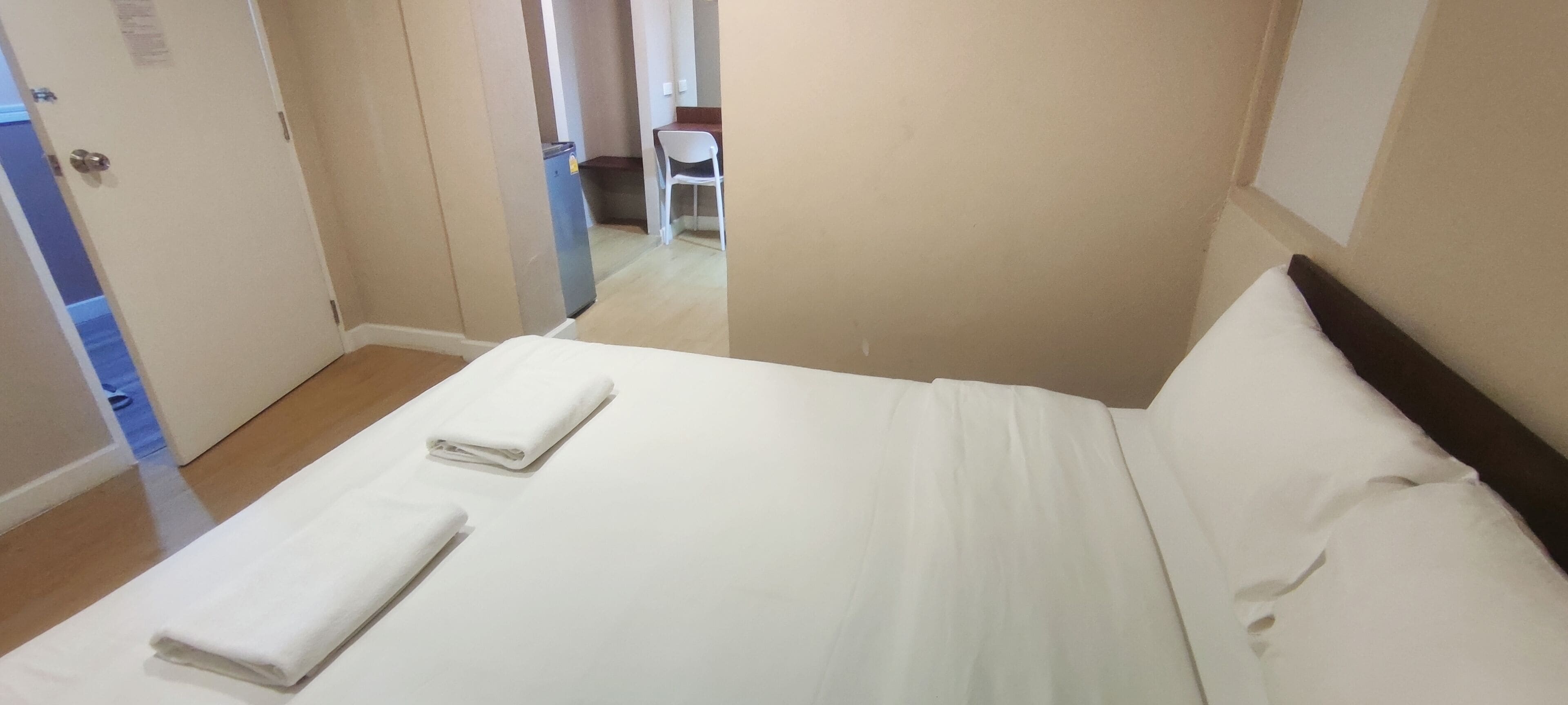 A hotel room with a bed, a desk, and a chair.