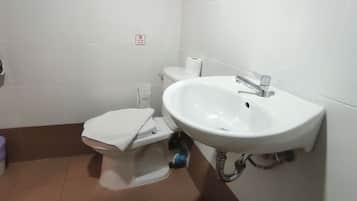 A small bathroom with a toilet, a sink, and a trash bin.