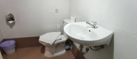 Un baño pequeño con inodoro, lavamanos y un cubo de basura.