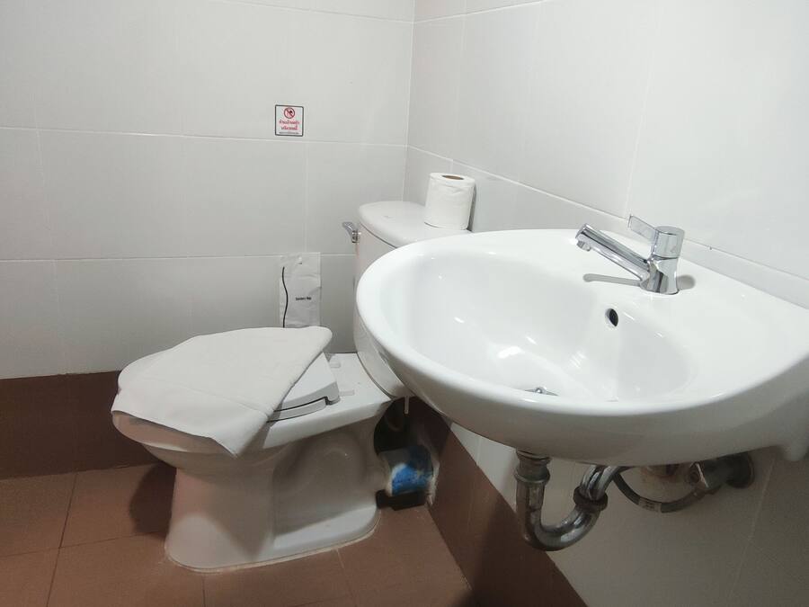 A small bathroom with a toilet, a sink, and a trash bin.