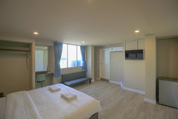 A hotel room with a bed, a bench, a desk, a chair, a TV, and a door. - The Sea Bangsaen Hotel (Chonburi)