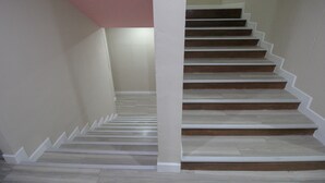 A staircase with wooden steps and white railings, leading to a landing with a pink ceiling.