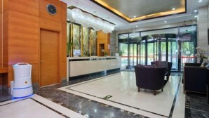 Un hall d’hôtel comprenant un comptoir d’accueil, une horloge, un espace d’accueil et un coin salon.
