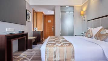 Une chambre d’hôtel comprenant un lit, un bureau, une chaise et une porte donnant sur une autre pièce.