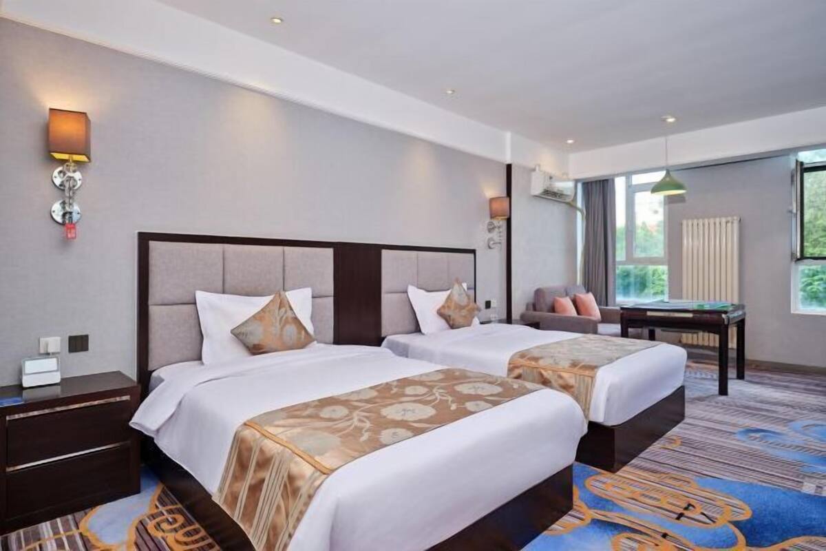 Een hotelkamer met twee bedden, een bureau, een stoel en een raam met uitzicht.