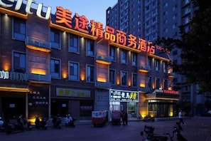 Un hôtel à étages, une enseigne bien visible avec des caractères chinois, et plusieurs boutiques situées au rez-de-chaussée.