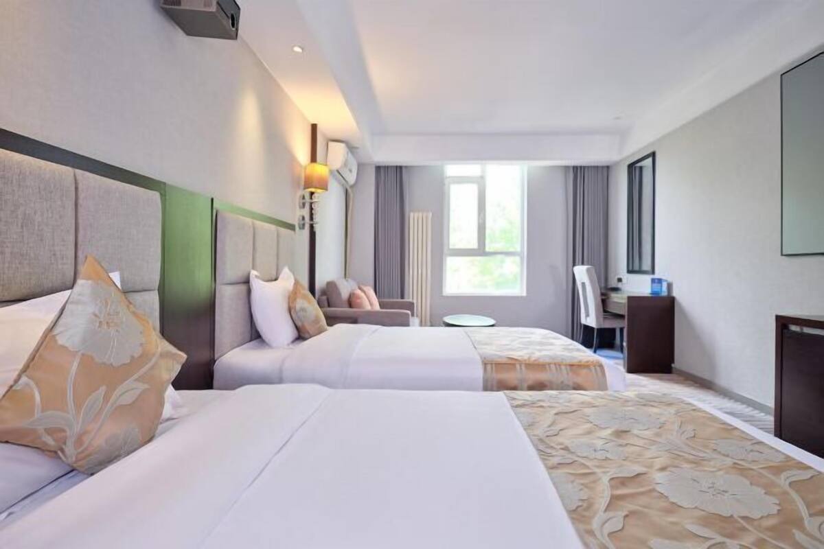 Een hotelkamer met twee bedden, een bureau, een stoel en een groot raam.