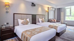 Une chambre d’hôtel avec deux lits, un canapé, une petite table et une fenêtre.