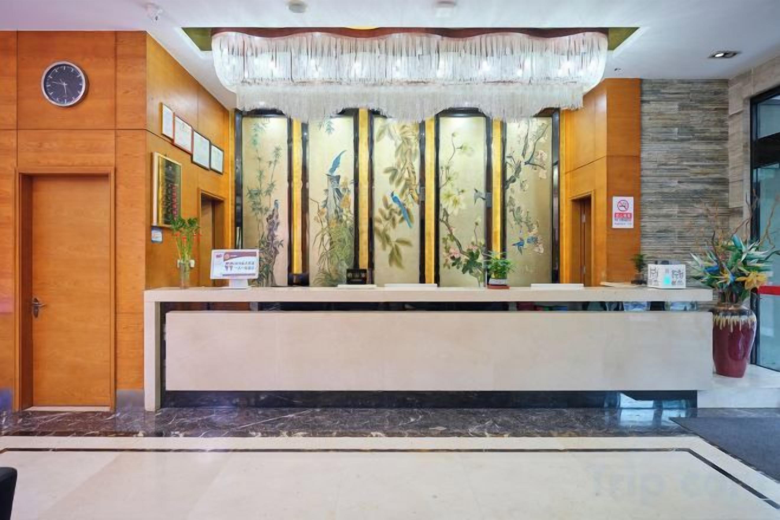 A reception desk with a clock, framed pictures, and a potted plant.