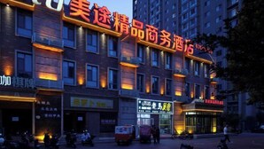 Un hôtel avec une enseigne bien visible en caractères chinois, plusieurs étages et un parking où sont stationnés des scooters.