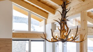 Une cuisine moderne avec des poutres en bois, de grandes fenêtres et un lustre orné de bois de cerf.