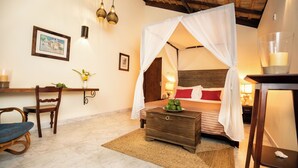Une chambre à coucher avec un lit à baldaquin, une table de chevet en bois, une chaise et une petite table de nuit avec une lampe.
