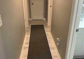 A hallway with a carpet leading to a white door.
