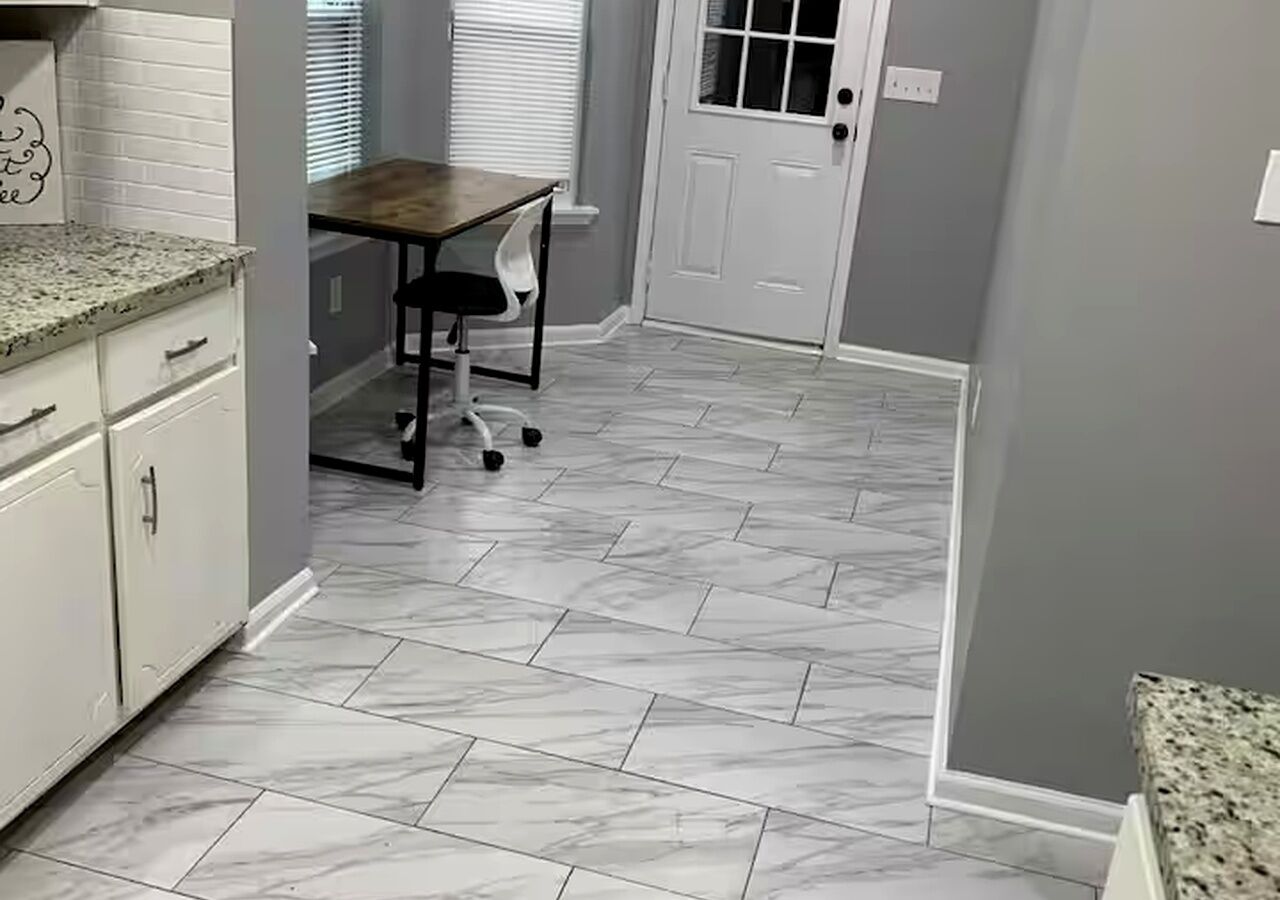 A kitchen with white cabinets, a granite countertop, and a tiled floor.