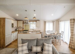 Amplia sala de estar con sofá, mesa de comedor y cocina al fondo.