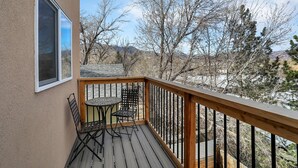 Una terraza de madera con una mesa y sillas, con vistas a un paisaje montañoso.