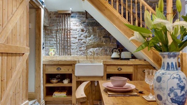 Eine rustikale Küche mit einer Steinwand, Holzschränken und einer Holztreppe.
