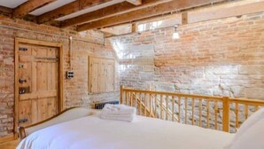 Ein Schlafzimmer mit freiliegenden Holzbalken, Steinwänden und einem hölzernen Bett.