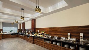A buffet setup with a variety of food items, wooden paneling, and hanging pendant lights. - Fortune Park, Hoshiarpur - Member ITC Hotels' Group (Hoshiarpur)