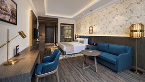 A modern hotel room with a bed, blue sofa, and a small table. - Fortune Park, Hoshiarpur - Member ITC Hotels' Group (Hoshiarpur)