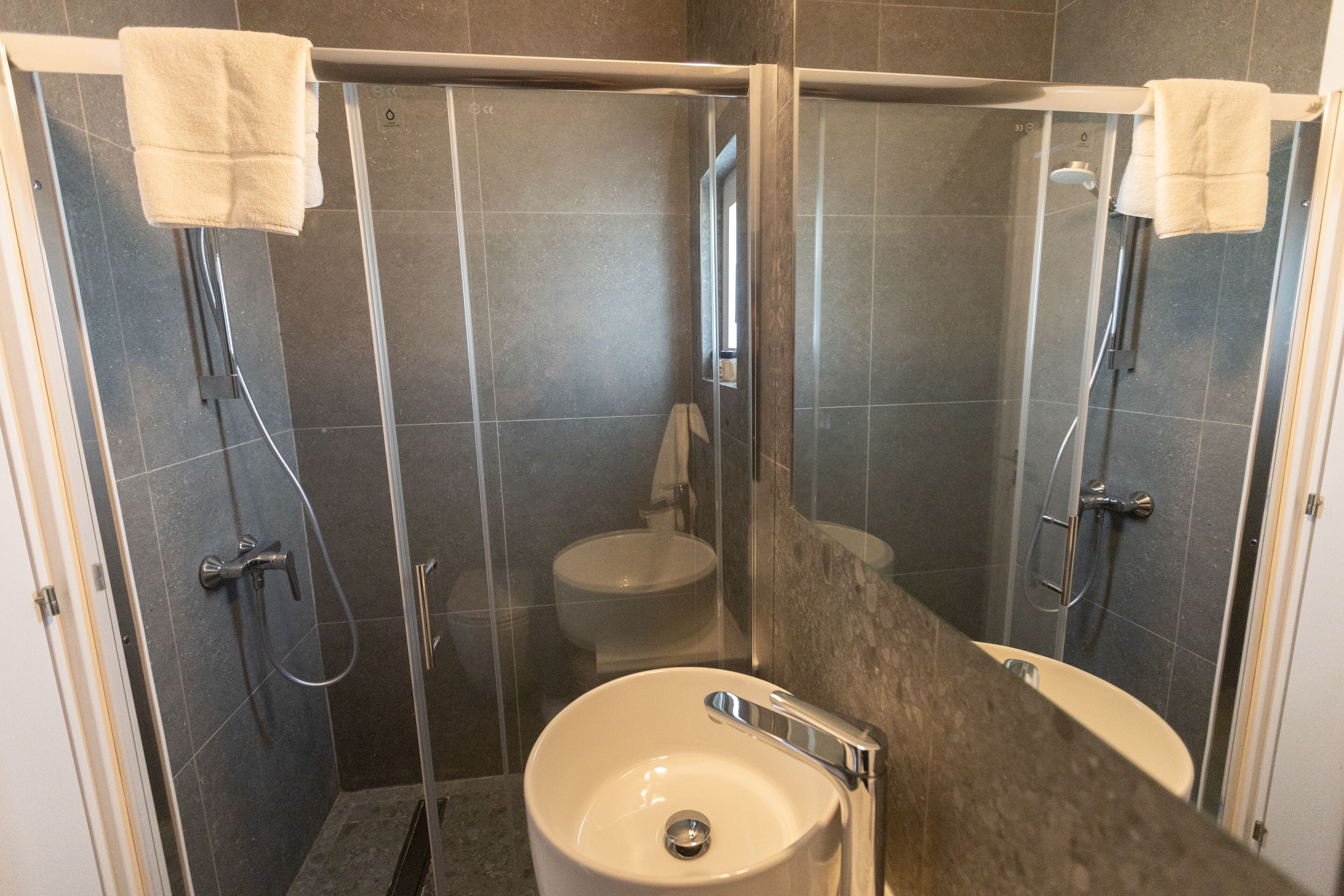 Et moderne badeværelse med bruseniche, vask og toilet.