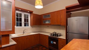 Een keuken met houten kastjes, een roestvrijstalen koelkast, een fornuis en een raam met gesatineerd glas.