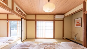 Una habitación japonesa tradicional con suelo de tatami, futón, puertas correderas y una linterna de papel colgante.