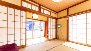Una habitación tradicional japonesa con suelo de tatami, puertas correderas shoji y una mesa baja con cojín.