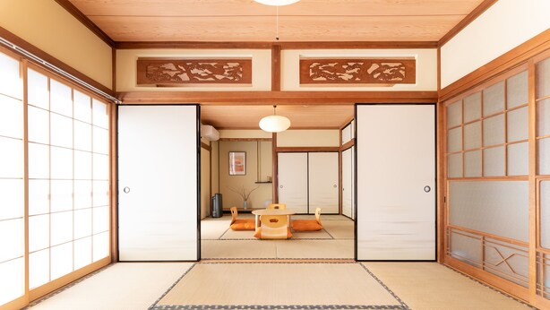 Una habitación japonesa tradicional con suelo de tatami, puertas correderas y una mesa baja de tatami en el centro.